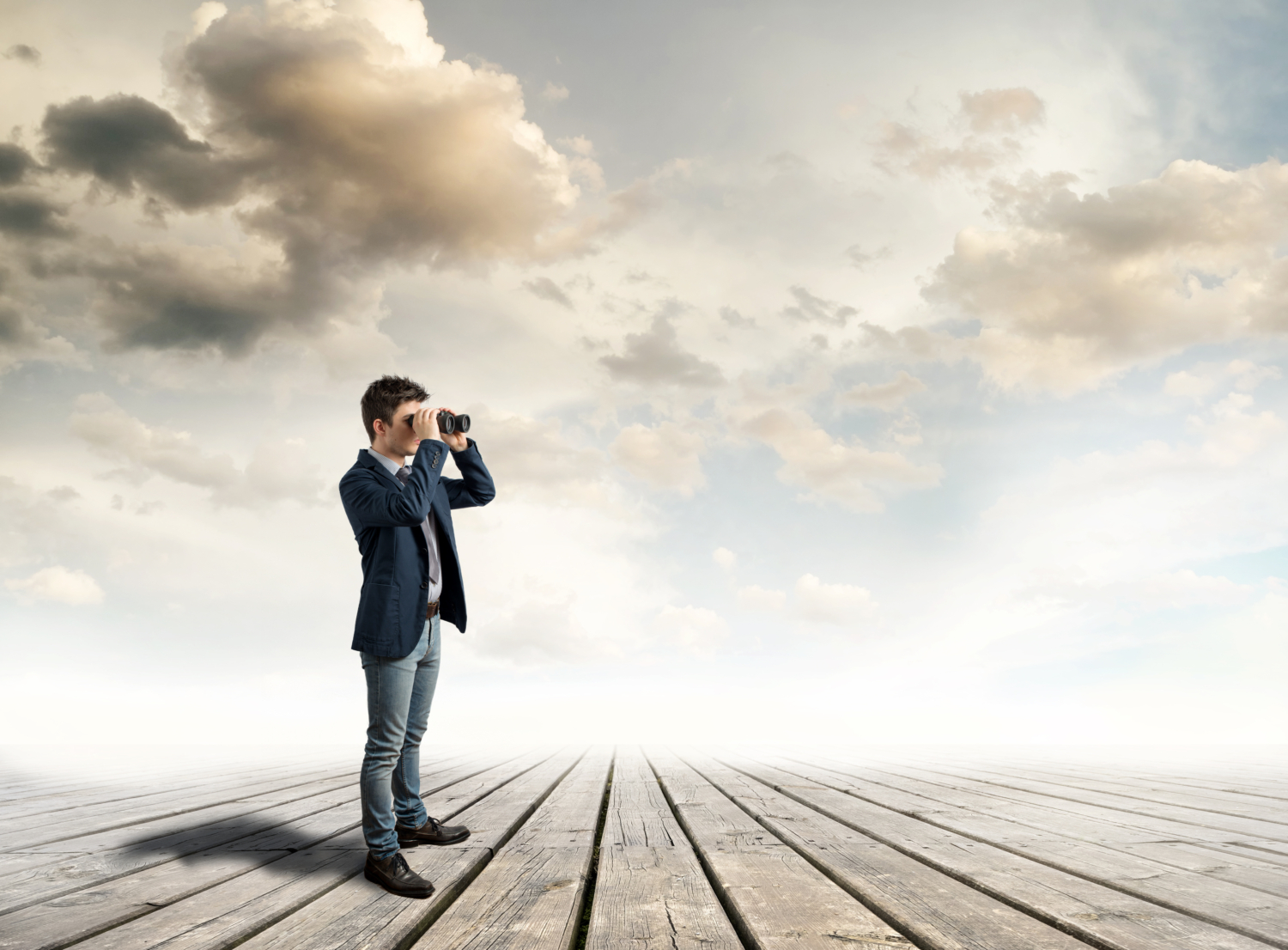 Ein Mann mit einem Fernglas schaut in die Ferne um ihn herum sind nur der Himmer und Wolken zu sehen. Er steht auf einem Holzplankenboden - Martina Wagner Immobilien
