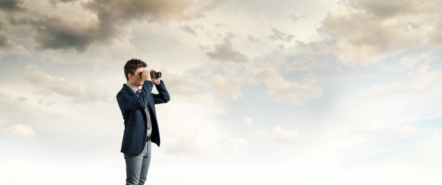 Ein Mann mit einem Fernglas schaut in die Ferne um ihn herum sind nur der Himmer und Wolken zu sehen. Er steht auf einem Holzplankenboden - Martina Wagner Immobilien