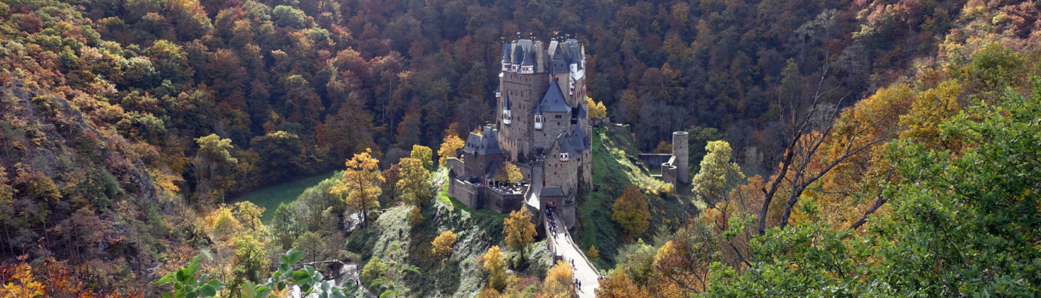 Blick aus der Vogelperspektive auf die Burg Eltz im Herbst mit Hügeln rund herum