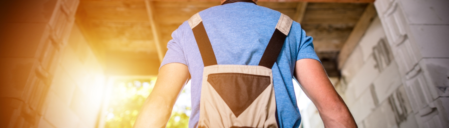 Pro Builder Ready For Work Ein Handwerker blickt auf den Rohbau eines Gebäudes er ist von hinten zu sehen - Martina Wagner Immobilien