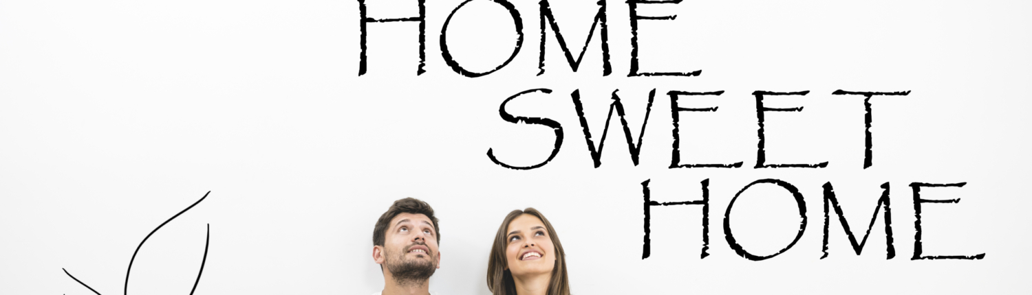 Home Sweet Home junges Paar sitzt vor einer Wand mit der Aufschrift "Home Sweet Home" - Martina Wagner Immobilien