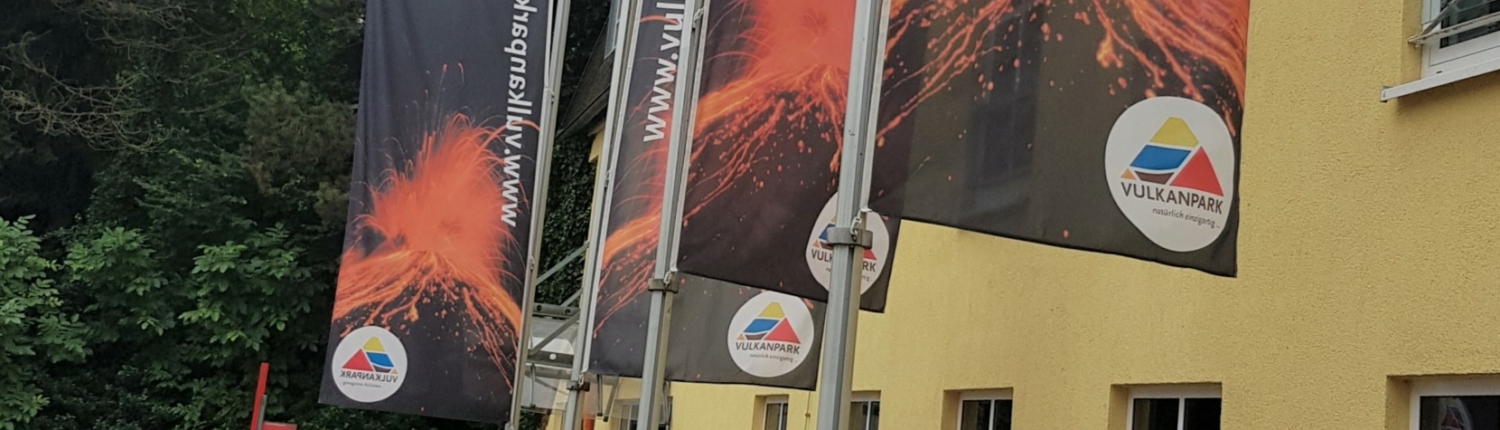 Das Gebäude des Vulkanpark Zentrums in Plaidt mit Flaggen im Vordergrund - Martina Wagner Immobilien