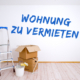 Eine leere Wohnung mit dem Anstrich "Wohnung zu Vermieten" und ein paar Umzugskartons und Streichutensilien im Vordergrund - Martina Wagner Immobilien