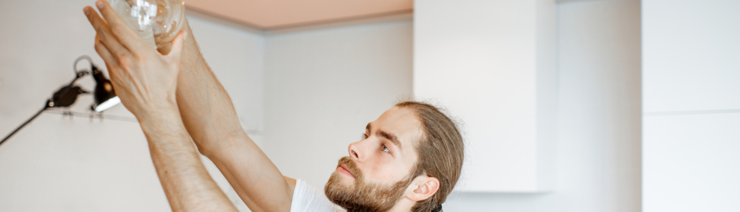Ein Handwerker schraubt eine Glühlampe ein - Martina Wagner Immobilien