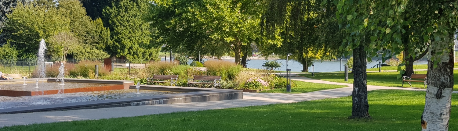 Bad Breisig Rheinanlagen Rheinanlagen Bad Breisig. Blick auf den Brunnen, den Rhein im Hintergrund und die Grünanalagen - Martina Wagner Immobilien