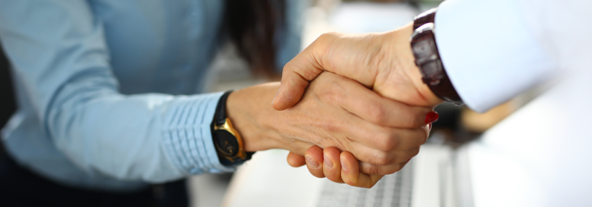 Nahaufnahme eines Handschlags zwischen einer Dame und einem Herren, beide im Businesslook - Martina Wagner Immobilien