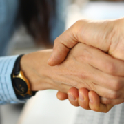 Nahaufnahme eines Handschlags zwischen einer Dame und einem Herren, beide im Businesslook - Martina Wagner Immobilien