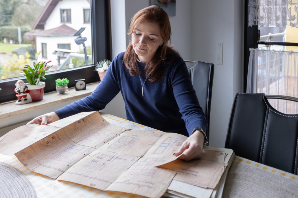 Martina Wagner sitzt an einem Tisch und schaut sich die Grundrisspläne einer Immobilie an