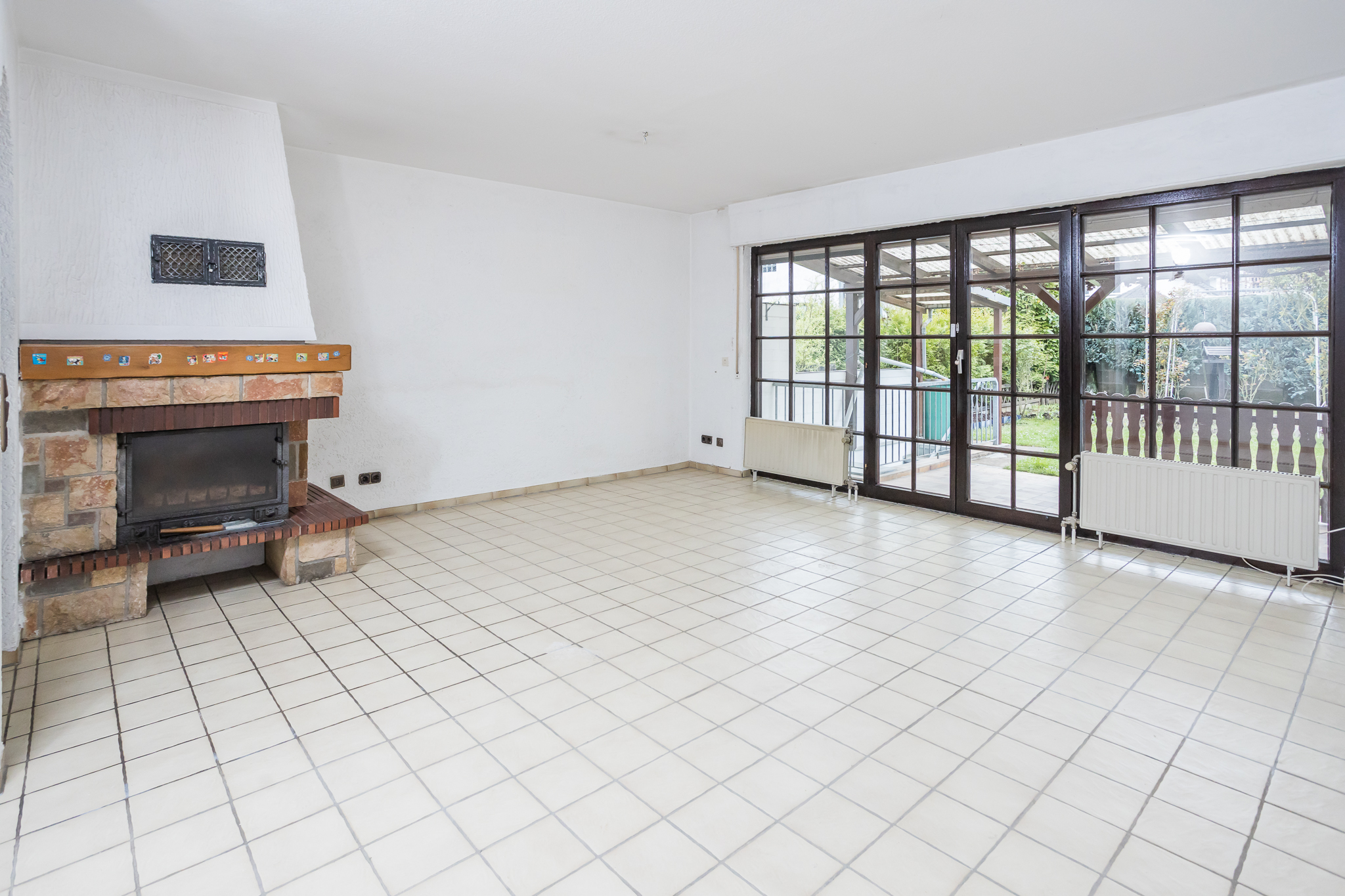 Wohnzimmer mit Blick auf Kamin und die Fensterfront zum Garten