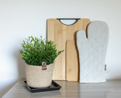 Schneidebretter, ein Kochhandschuh sowie eine Pflanze als Küchendeko - Martina Wagner Immobilien