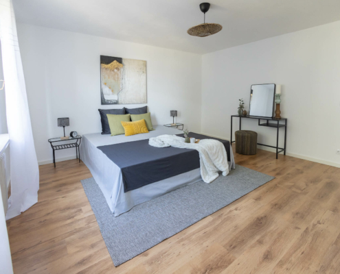 großzügiges helles Schlafzimmer großes Schlafzimmer mit Bett in der Mitte, Fenster links und Schminkecke rechts - Martina Wagner Immobilien