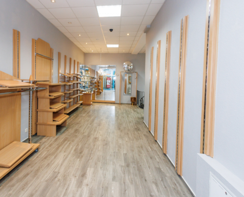 hinterer Teil Ladenlokal, Rückwand Spiegel, Links einige Regale, rechts Wand mit Paneelen