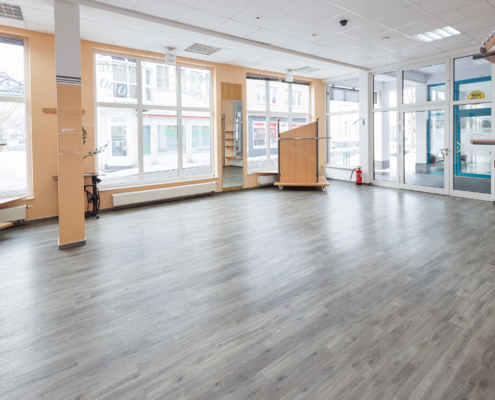 Blick auf Schaufenster und einen Eingangsbereich mit großer Glastür, heller Vinylboden