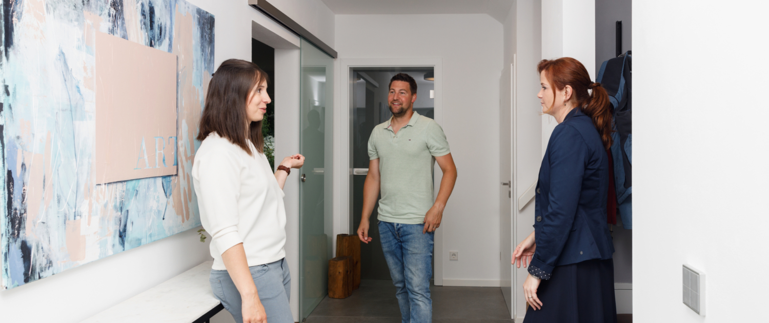 Martina Wagner im Kundengespräch im Eingangsbereich eines modernen Wohnhauses