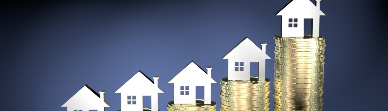 Finanzierung 5 kleine silber farbene Häuser stehen auf Münzstapeln, die von links nach rechts größer werden