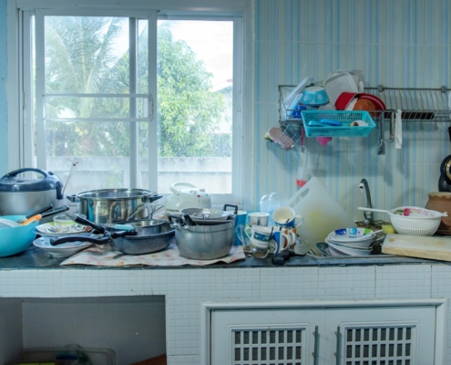 unaufgeräumte Küchenzeile mit dreckigem Geschirr, Töpfen und Co, Fenster im Hintergrund
