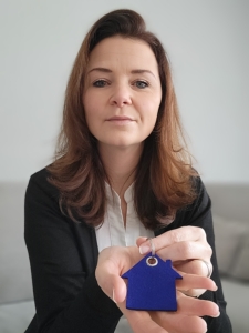 Martina Martina Wagner hält einen Schlüsselanhänger mit einem blauen Haus aus Filz in der Hand