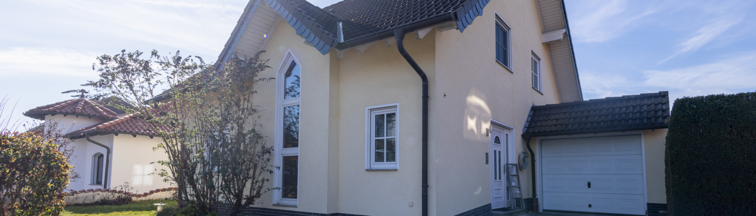 Seitliche Außenansicht der Immobilie in Oberlützingen. Gepflasterte Einfahrt, Garage und Vorgarten sind zu sehen