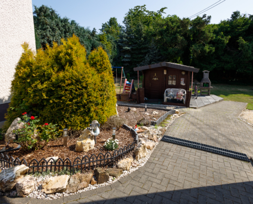 ansprechend angelegter Weg in den Garten Blick auf einen gepflasterten Weg mit Beet und Gartenhaus links