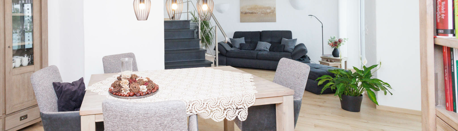 Blick auf einen Essbereich, heller Holzfußboden, Natursteintreppe und modernes Mobiliar