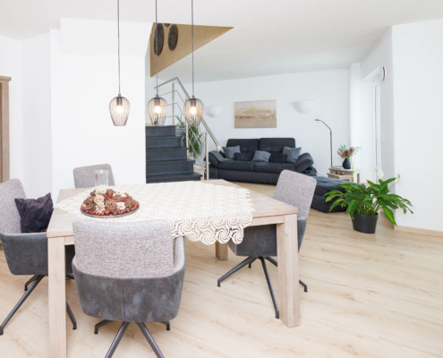 Blick auf einen Essbereich, heller Holzfußboden, Natursteintreppe und modernes Mobiliar