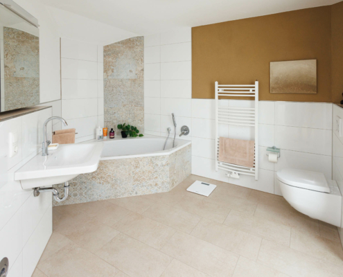 Bad mit Eckwanne, und Waschbecken mit Spiegelschrank links, rechts Handtuchwärmer und Toilette.