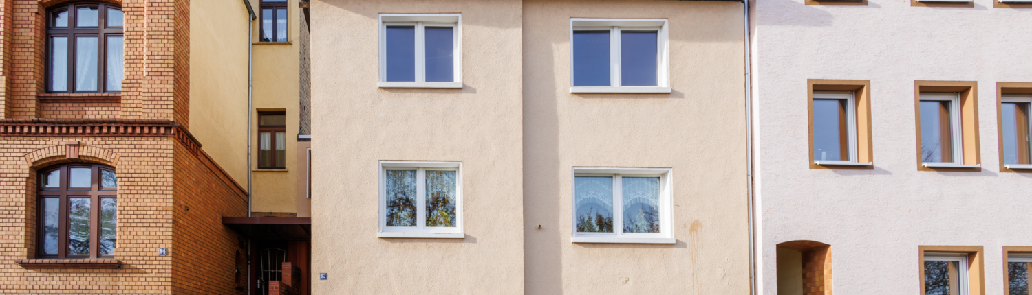 Frontansicht Häuserzeile, mit einem kleineren Gebäude mit Flachdach in der Mitte.