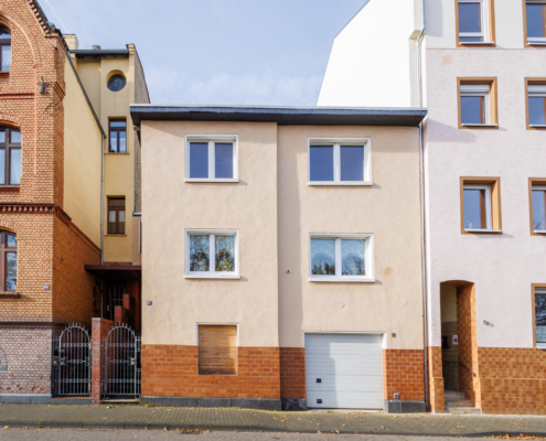 Frontansicht Immobilie Frontansicht Häuserzeile, mit einem kleineren Gebäude mit Flachdach in der Mitte.