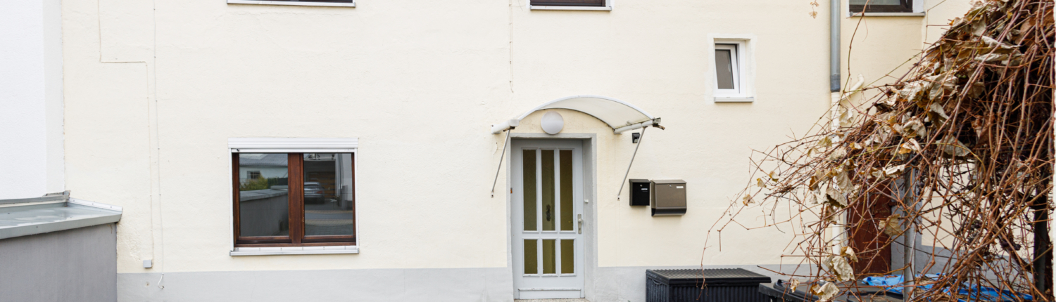 Frontansicht einer Altbauimmobilie mit Hof im Vordergrund.