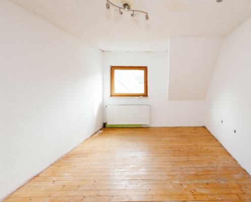 helles weißes Zimmer (Decke und Wände) mit Echtholzdielenboden, hinten Fenster, darunter Heizkörper