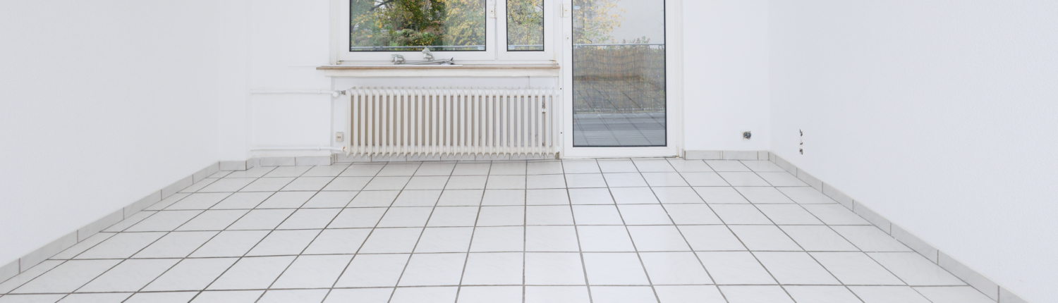 Wohnzimmer mit weißen Fliesen, Wänden und Decke, zentral ein Fenster mit Balkontür darunter ein Heizkörper