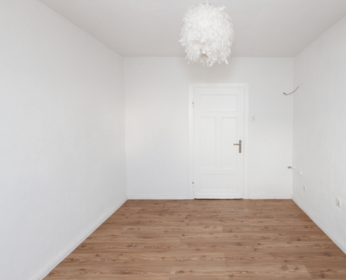 Raum mit weißer Decke, weißen Wänden, weißer Zimmertür, Boden dunkles Holz