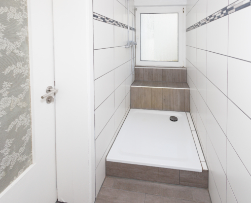 Bad mit Dusche in moderner Gestaltung hinten Fenster, links Tür